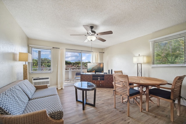 living room featuring a textured ceiling, ceiling fan, an AC wall unit, and hardwood / wood-style flooring