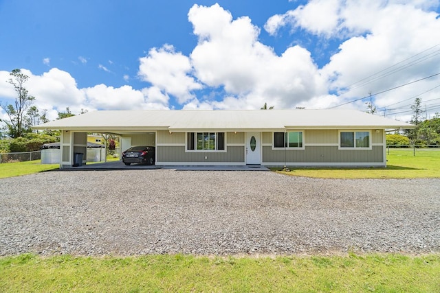 ranch-style home featuring gravel driveway, a front lawn, and a carport