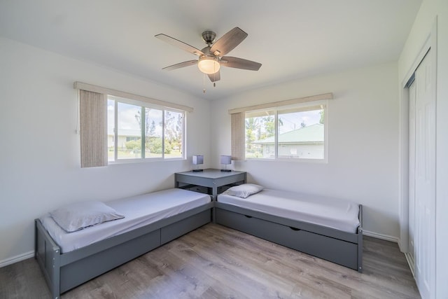 sitting room featuring light wood-style floors, baseboards, and a ceiling fan