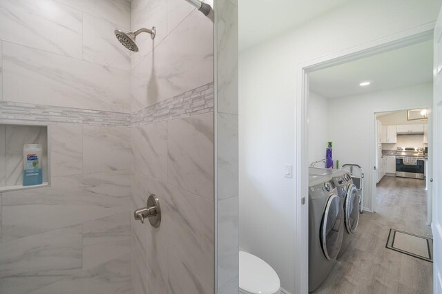 bathroom featuring tiled shower, toilet, independent washer and dryer, and wood-type flooring