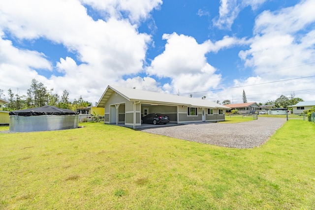 rear view of house featuring a carport, a lawn, and driveway