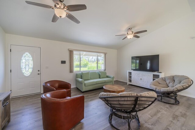 living room with ceiling fan, hardwood / wood-style flooring, and vaulted ceiling