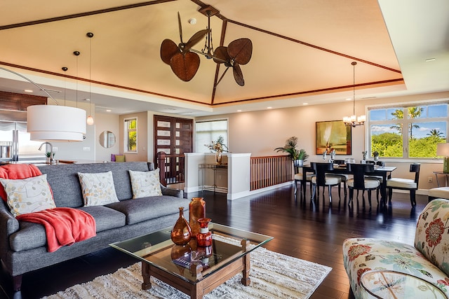 living room featuring an inviting chandelier, a tray ceiling, and dark hardwood / wood-style floors