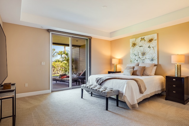 bedroom featuring light carpet, a tray ceiling, and access to exterior