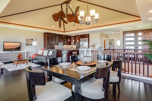 dining room featuring a raised ceiling, sink, dark wood-type flooring, and a chandelier