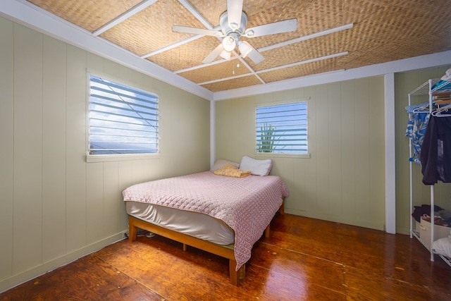 bedroom with ceiling fan, wooden walls, and dark hardwood / wood-style flooring