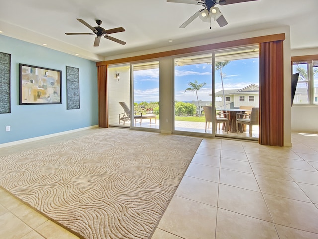 empty room with a healthy amount of sunlight, light tile patterned flooring, and ceiling fan