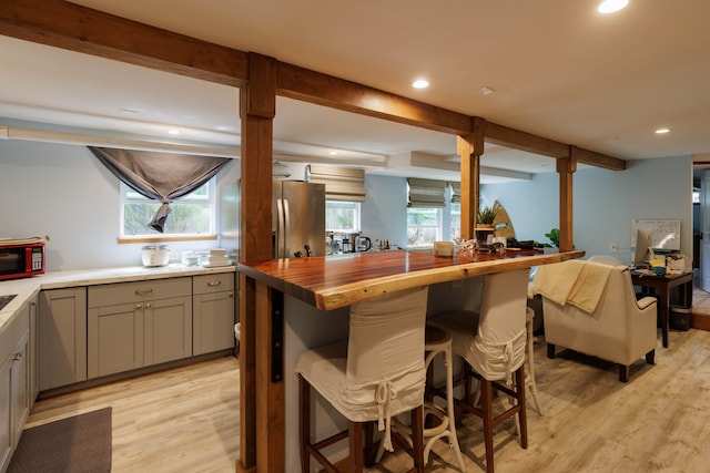 kitchen featuring butcher block countertops, a breakfast bar area, a wealth of natural light, and light hardwood / wood-style floors