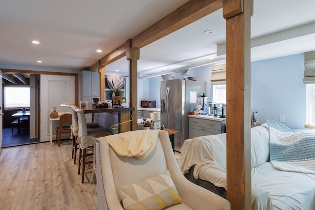 interior space with light wood-type flooring, stainless steel fridge with ice dispenser, and gray cabinetry