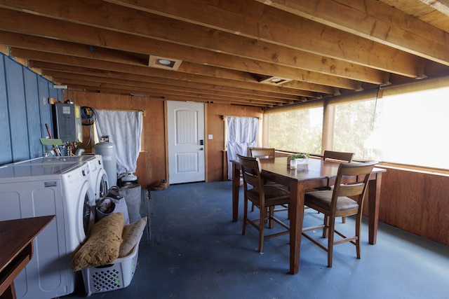 interior space with wood walls, washing machine and clothes dryer, concrete flooring, and electric panel