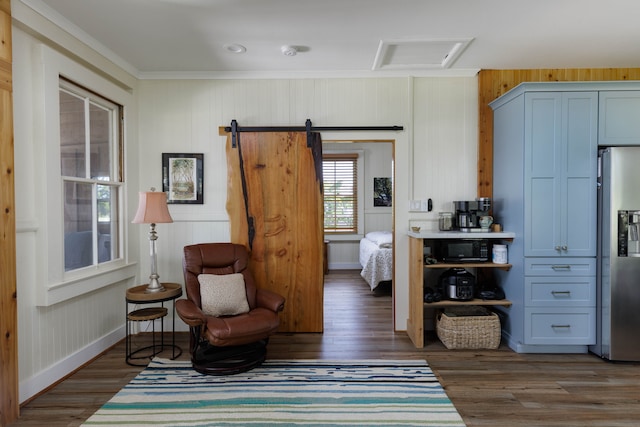 living area featuring a barn door, wooden walls, and dark hardwood / wood-style flooring