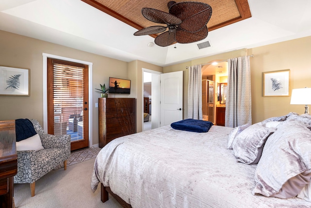 carpeted bedroom with a tray ceiling, ensuite bathroom, and ceiling fan