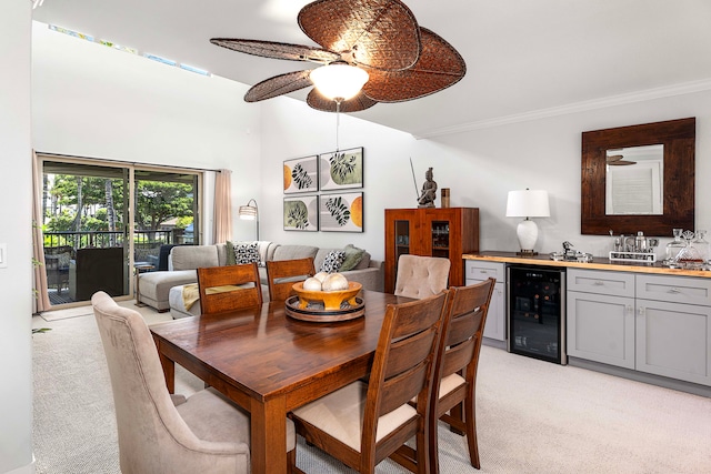 dining room with bar, beverage cooler, light carpet, ornamental molding, and ceiling fan