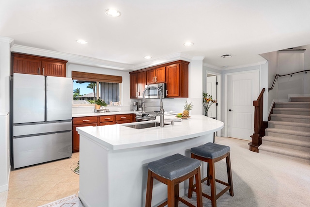 kitchen with a kitchen breakfast bar, appliances with stainless steel finishes, kitchen peninsula, ornamental molding, and light tile patterned flooring