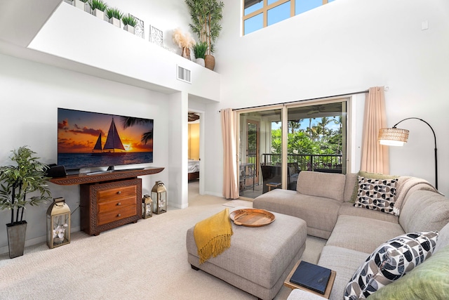 carpeted living room featuring a healthy amount of sunlight and a high ceiling