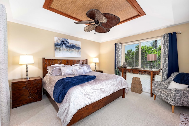 carpeted bedroom featuring a tray ceiling and ceiling fan