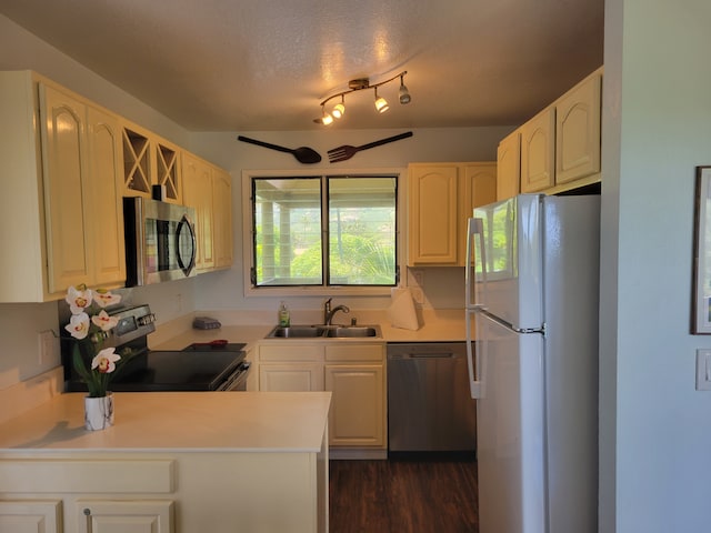 kitchen with dark hardwood / wood-style floors, sink, rail lighting, a textured ceiling, and stainless steel appliances