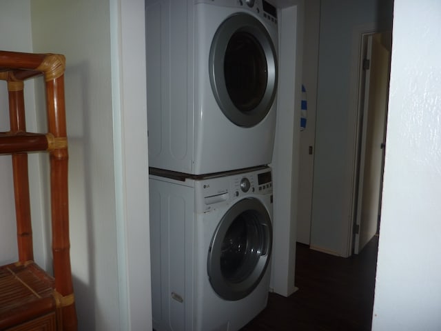 washroom featuring stacked washer / drying machine and dark hardwood / wood-style floors