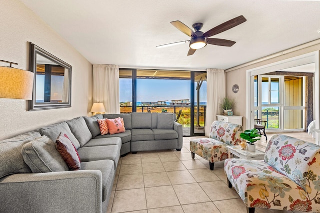 living room with light tile patterned flooring, ceiling fan, and a wall of windows