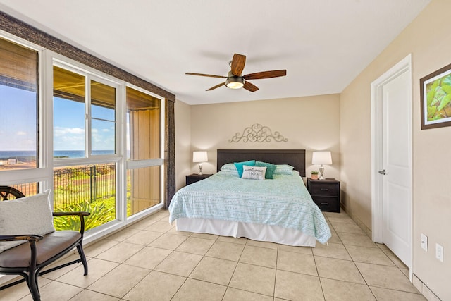 tiled bedroom with ceiling fan, multiple windows, and a water view