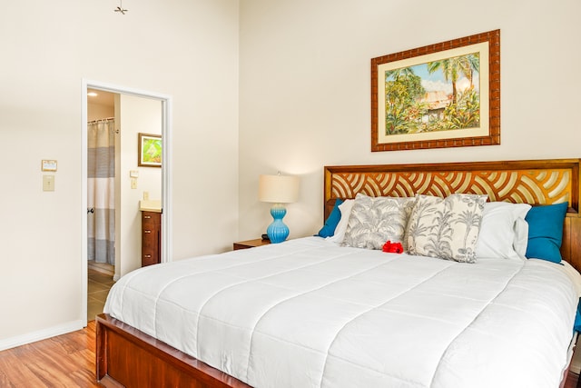 bedroom with ensuite bathroom and light hardwood / wood-style floors