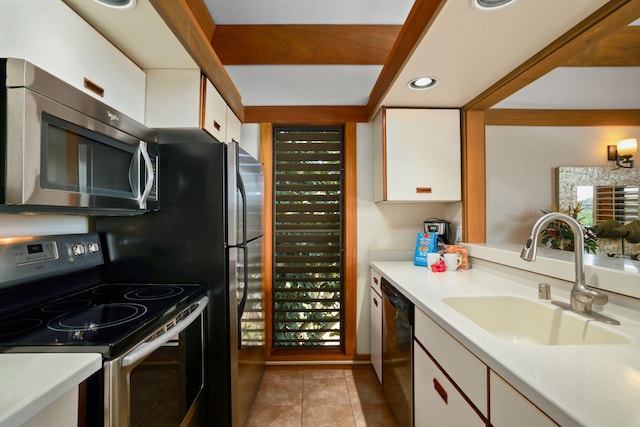 kitchen with sink, white cabinets, appliances with stainless steel finishes, and light tile patterned floors