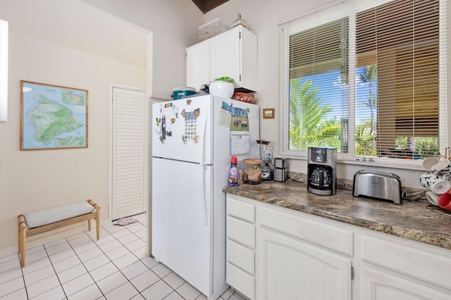 kitchen featuring freestanding refrigerator, white cabinets, and light tile patterned floors