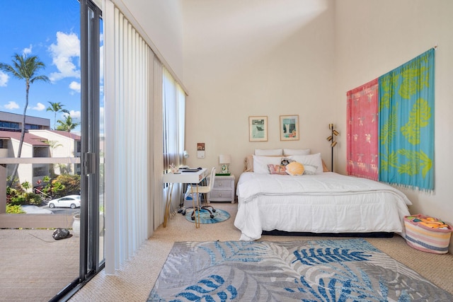 bedroom with a high ceiling, multiple windows, carpet, and access to exterior