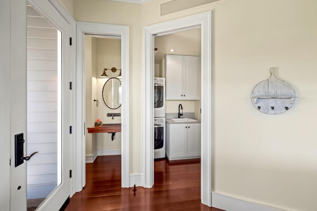 hall featuring stacked washing maching and dryer, dark hardwood / wood-style floors, and sink