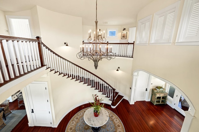 staircase featuring hardwood / wood-style floors, a notable chandelier, and a high ceiling