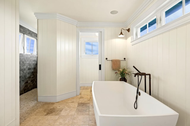 bathroom with tile patterned floors, wood walls, a bathtub, and ornamental molding