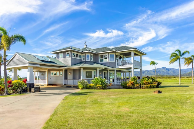 view of front facade featuring solar panels, covered porch, a mountain view, and a front lawn