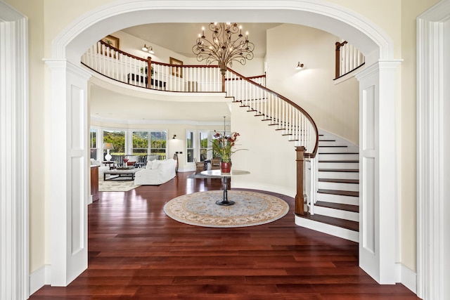 entrance foyer with a towering ceiling, dark hardwood / wood-style floors, and an inviting chandelier