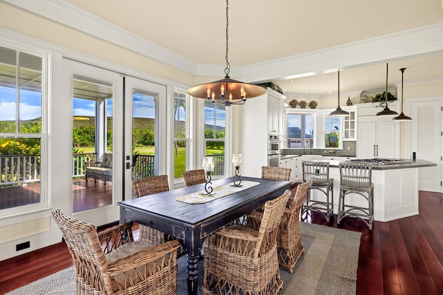 dining space featuring dark hardwood / wood-style floors, an inviting chandelier, and ornamental molding