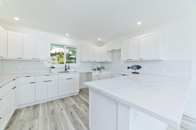 kitchen featuring white cabinets, sink, and light hardwood / wood-style floors