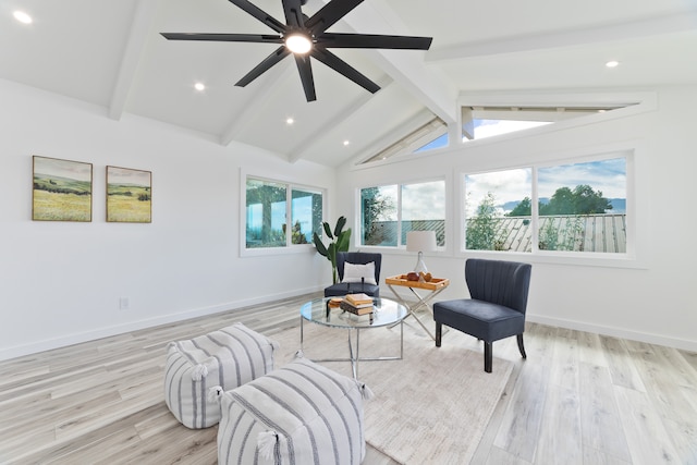 sitting room featuring light hardwood / wood-style floors, vaulted ceiling with beams, a wealth of natural light, and ceiling fan