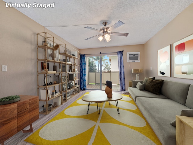 living room featuring a textured ceiling, ceiling fan, hardwood / wood-style floors, and a wall mounted air conditioner