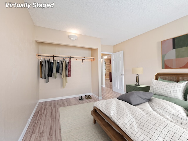 bedroom featuring light wood-type flooring, a closet, and a textured ceiling