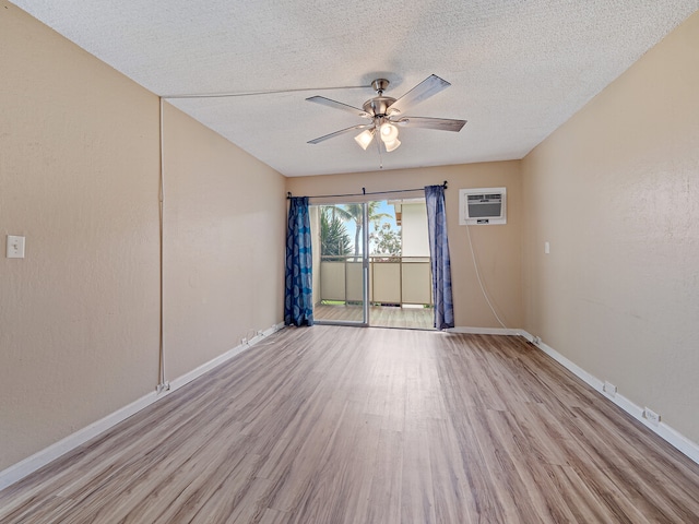 spare room with light wood-type flooring, a textured ceiling, an AC wall unit, and ceiling fan