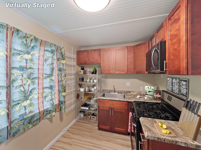 kitchen with range with gas stovetop, light wood-type flooring, light stone counters, and sink