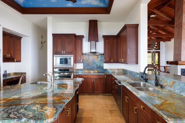 kitchen with stone counters, stainless steel appliances, wall chimney exhaust hood, and sink