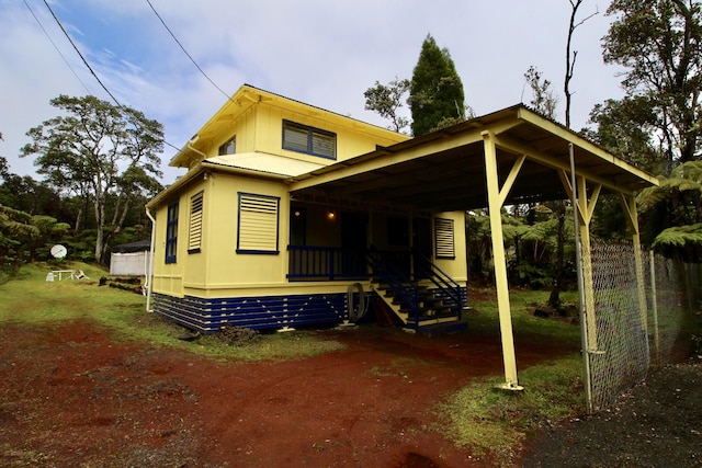 view of front of home featuring a carport, covered porch, and fence