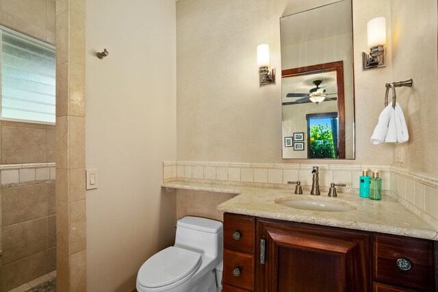 bathroom with ceiling fan, a tile shower, backsplash, toilet, and vanity