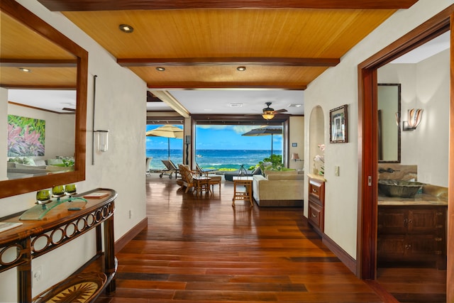 corridor with sink, beamed ceiling, a water view, dark wood-type flooring, and wooden ceiling