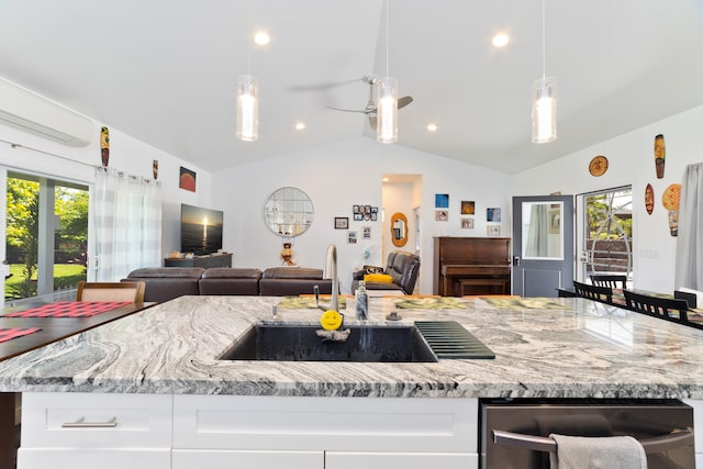 kitchen featuring light stone counters, sink, lofted ceiling, an island with sink, and ceiling fan