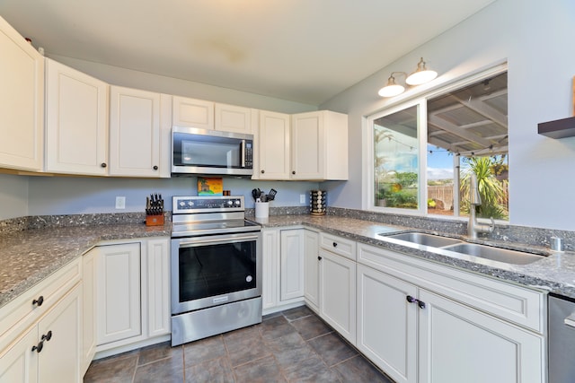 kitchen featuring dark stone countertops, appliances with stainless steel finishes, and white cabinets