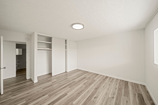 unfurnished bedroom with a textured ceiling, hardwood / wood-style flooring, and a closet