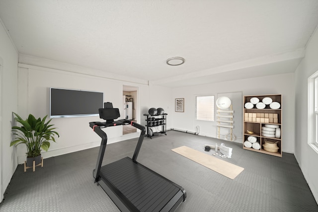 workout room with a healthy amount of sunlight and dark carpet