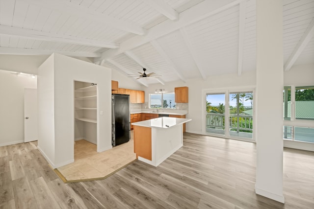 kitchen with light wood-type flooring, vaulted ceiling with beams, decorative backsplash, and black fridge