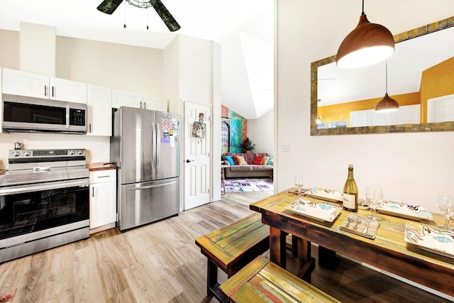 kitchen with light wood finished floors, appliances with stainless steel finishes, white cabinetry, vaulted ceiling, and ceiling fan